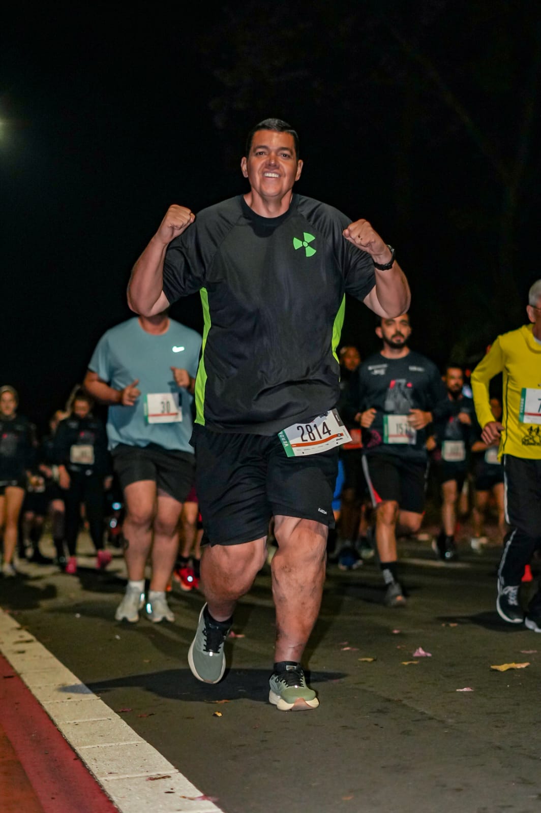Júlio Prado comemorando de braços erguidos durante corrida noturna, símbolo da transformação do Protocolo GV